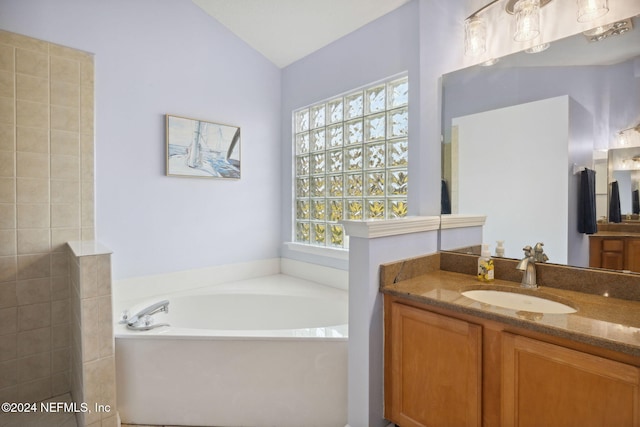 bathroom featuring a bathing tub, vanity, and vaulted ceiling