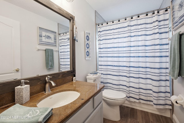 full bathroom featuring hardwood / wood-style floors, vanity, shower / tub combo, and toilet