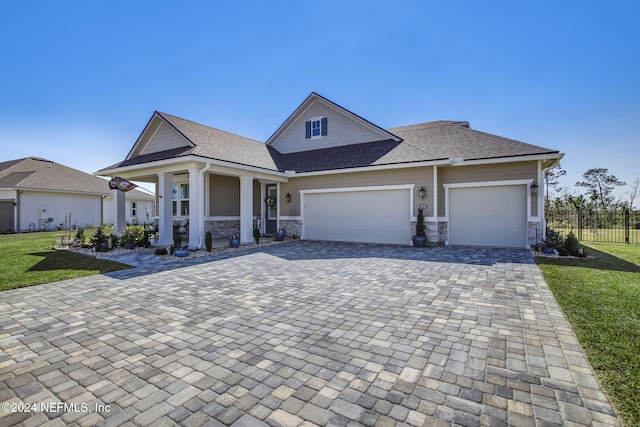 view of front of property with covered porch, a garage, and a front lawn