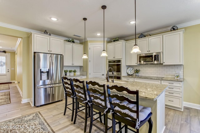 kitchen with pendant lighting, a kitchen island with sink, light wood-type flooring, light stone counters, and stainless steel appliances