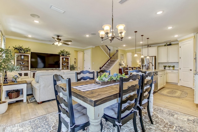 dining room featuring ceiling fan with notable chandelier, light hardwood / wood-style floors, and crown molding