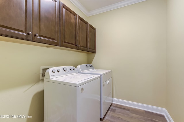 laundry area featuring light hardwood / wood-style floors, cabinets, ornamental molding, and washing machine and clothes dryer