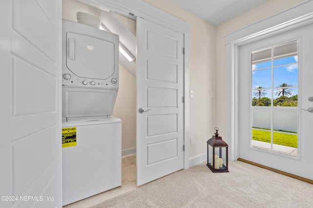 laundry area featuring light carpet and stacked washer and dryer