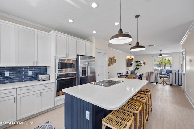 kitchen featuring a center island, white cabinetry, hanging light fixtures, and appliances with stainless steel finishes