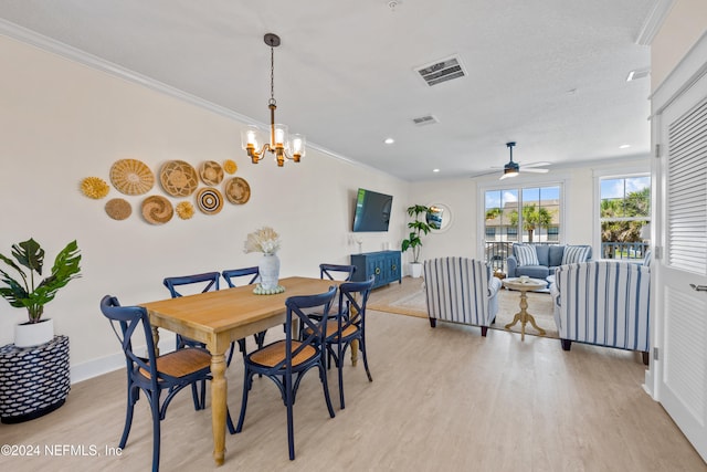 dining area with ceiling fan with notable chandelier, a textured ceiling, light wood-type flooring, and crown molding