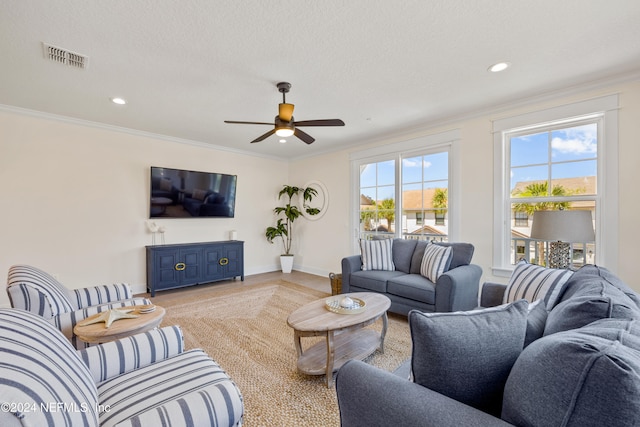 living room with plenty of natural light, ornamental molding, and ceiling fan