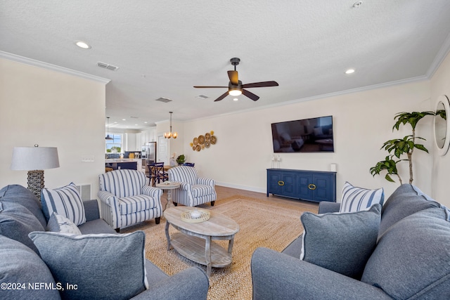 living room with crown molding, ceiling fan with notable chandelier, and a textured ceiling