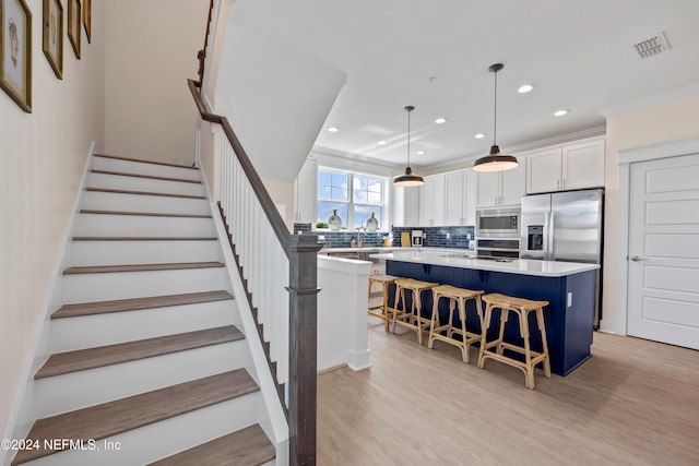 stairway featuring hardwood / wood-style floors, ornamental molding, and sink