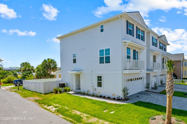 exterior space featuring central AC unit, a garage, and a front lawn