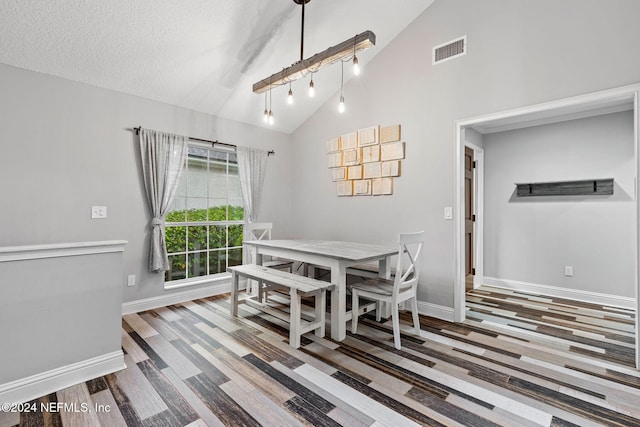 dining room with hardwood / wood-style flooring, a textured ceiling, and high vaulted ceiling