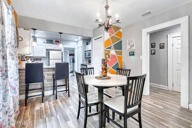 dining room featuring light wood-type flooring and a notable chandelier