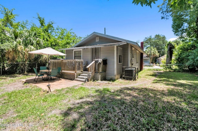 rear view of property with a lawn, cooling unit, and a patio