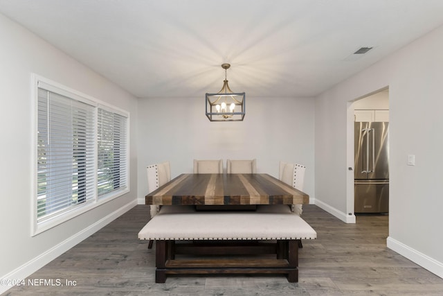 dining area with dark wood-type flooring and a notable chandelier