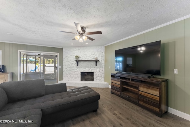 living room featuring a textured ceiling, ornamental molding, hardwood / wood-style flooring, ceiling fan, and a fireplace