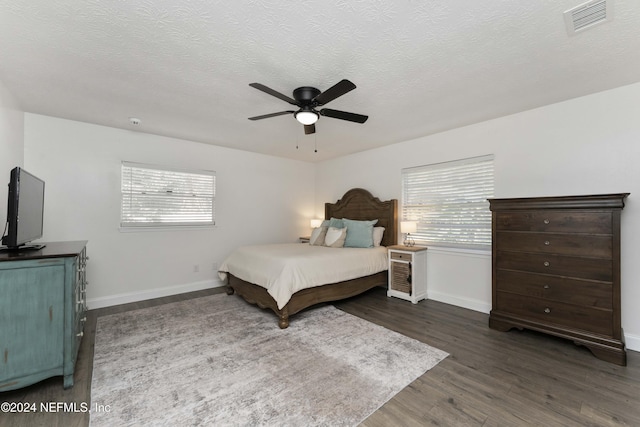 bedroom featuring dark wood-type flooring, ceiling fan, and a textured ceiling