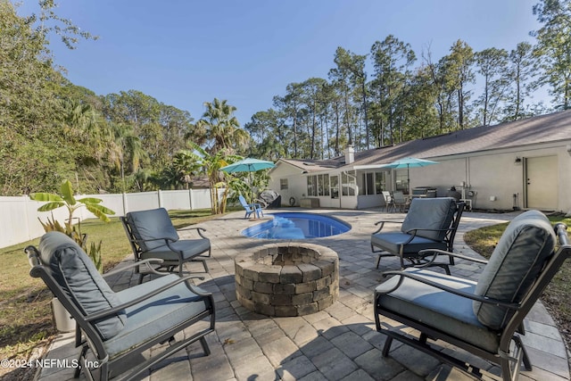 view of patio featuring a sunroom, a fenced in pool, and a fire pit