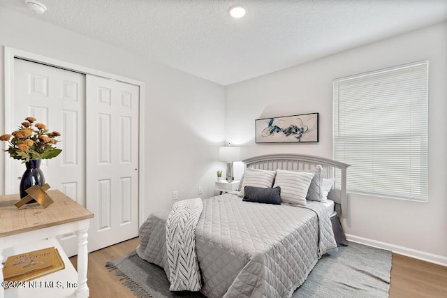 bedroom with wood-type flooring, a textured ceiling, and a closet