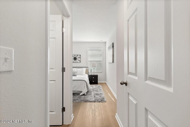 hall with a textured ceiling and light hardwood / wood-style floors