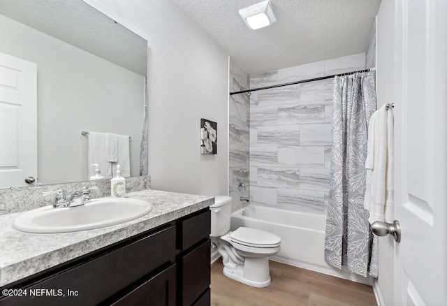 full bathroom with vanity, hardwood / wood-style flooring, toilet, shower / bath combo with shower curtain, and a textured ceiling