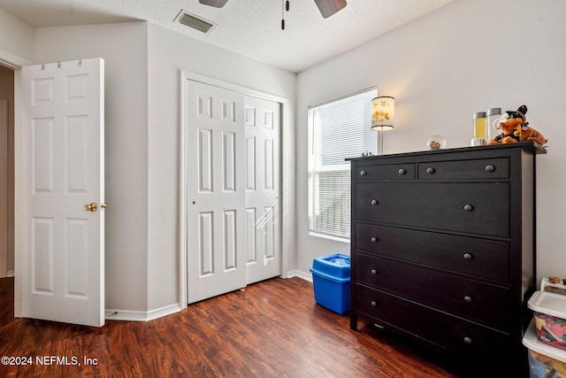 bedroom with ceiling fan, dark hardwood / wood-style flooring, a textured ceiling, and a closet