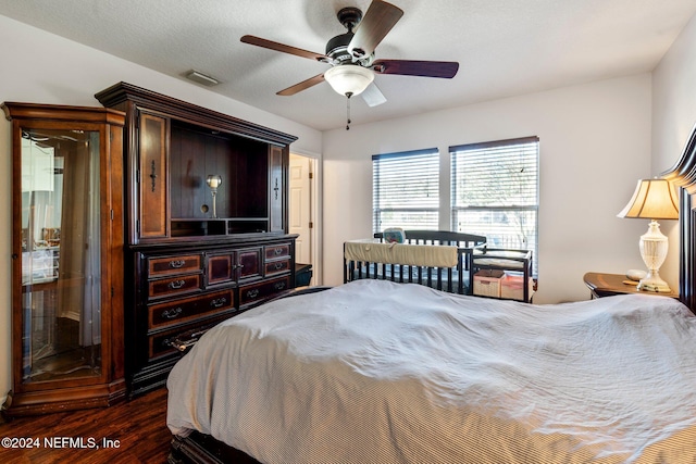 bedroom with a textured ceiling, dark hardwood / wood-style floors, and ceiling fan