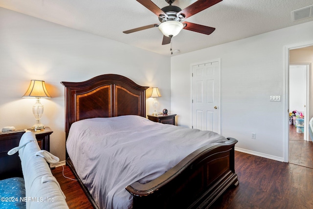 bedroom with a textured ceiling, ceiling fan, and dark wood-type flooring