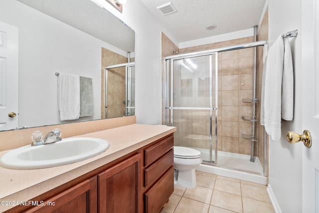 bathroom featuring tile patterned flooring, a textured ceiling, toilet, vanity, and a shower with shower door