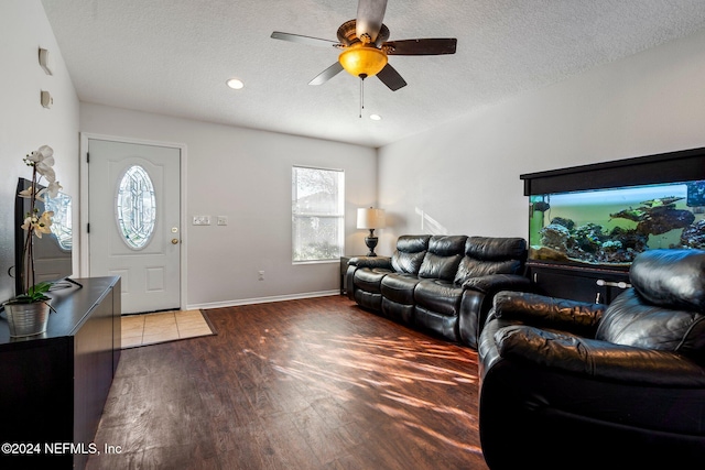 living room with dark hardwood / wood-style floors, ceiling fan, and a textured ceiling