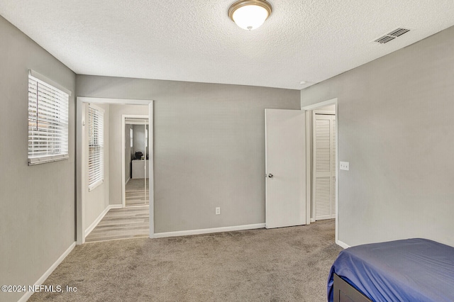 bedroom featuring light colored carpet and a textured ceiling