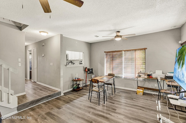 dining area with ceiling fan, wood-type flooring, and a textured ceiling