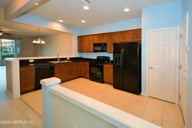 kitchen featuring pendant lighting, black appliances, ceiling fan with notable chandelier, sink, and kitchen peninsula