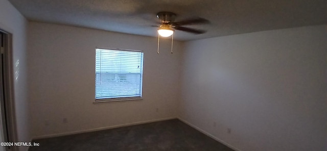 empty room featuring ceiling fan and dark carpet