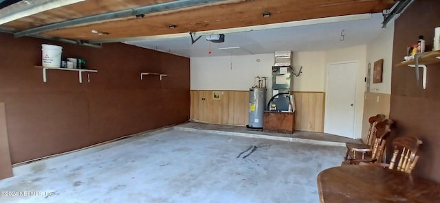 garage featuring heating unit, water heater, a garage door opener, and wood walls