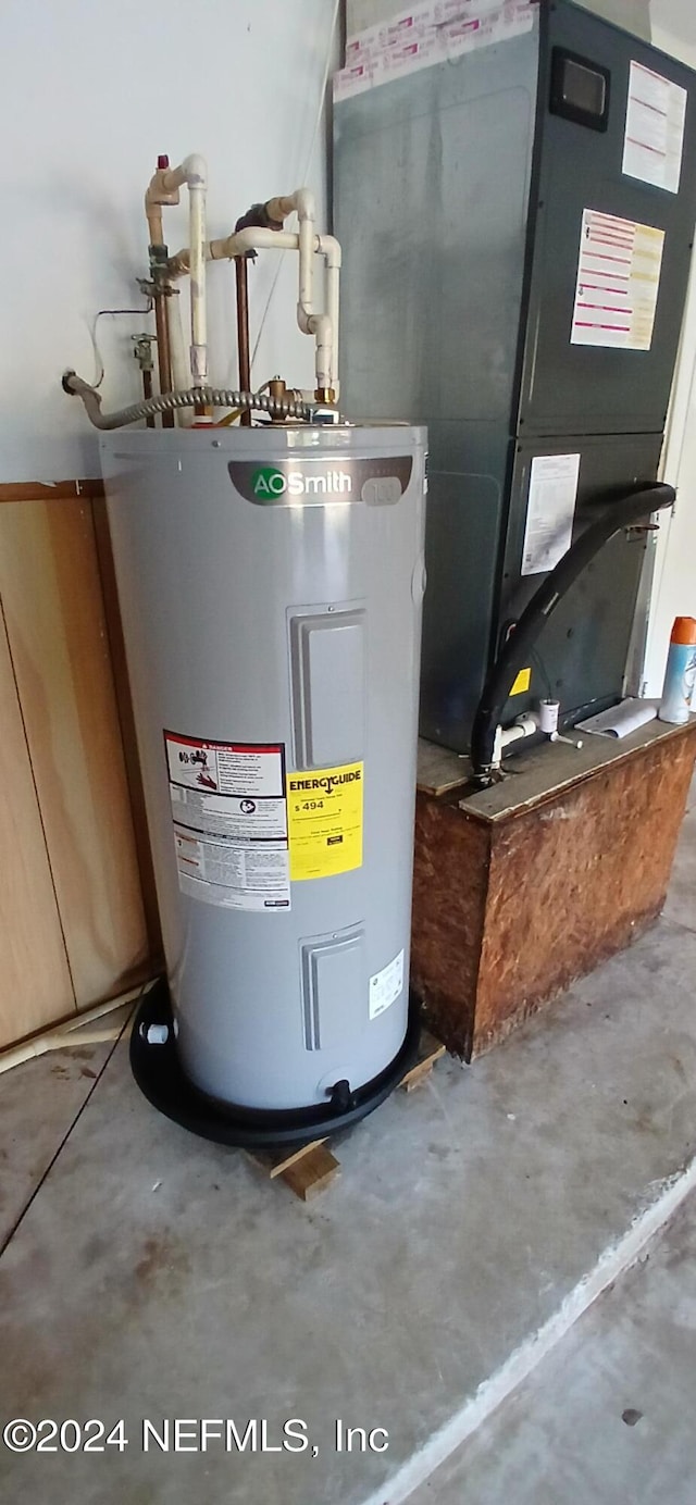 utility room with heating unit and electric water heater