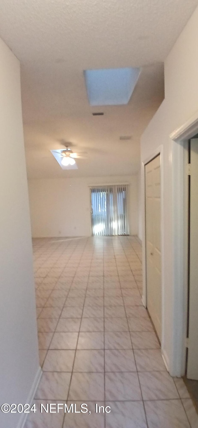 hallway with a skylight and light tile patterned floors