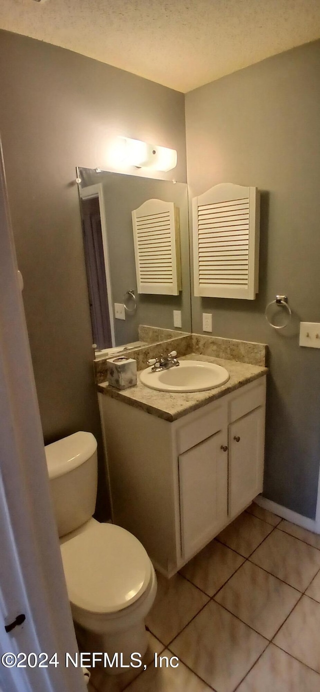 bathroom featuring tile patterned floors, vanity, toilet, and a textured ceiling