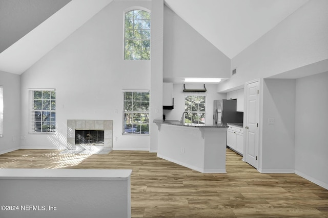 kitchen featuring kitchen peninsula, a healthy amount of sunlight, high vaulted ceiling, white cabinets, and light hardwood / wood-style floors