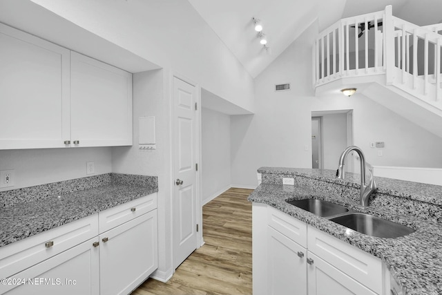 kitchen featuring sink, white cabinets, light hardwood / wood-style floors, and stone countertops