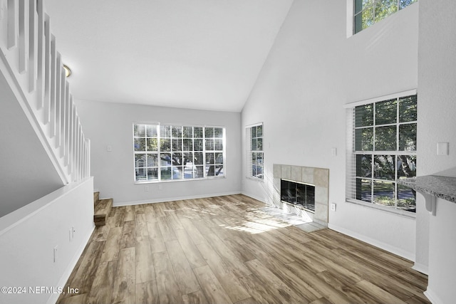 unfurnished living room with hardwood / wood-style floors, high vaulted ceiling, and a tile fireplace