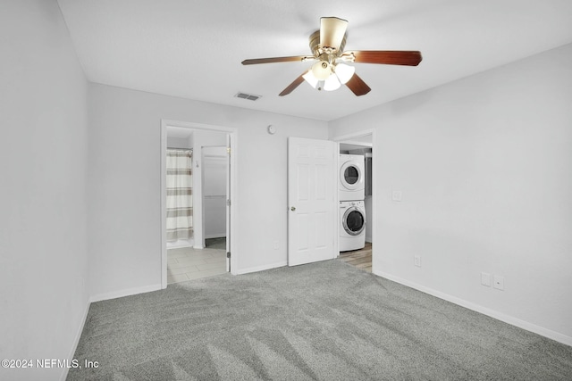 carpeted empty room with ceiling fan and stacked washer and dryer