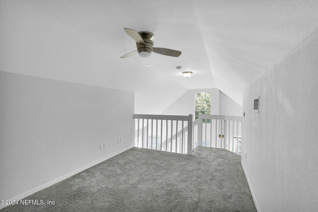 interior space featuring a textured ceiling, ceiling fan, carpet, and lofted ceiling