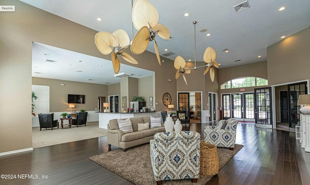 living room featuring ceiling fan, a towering ceiling, dark wood-type flooring, and french doors