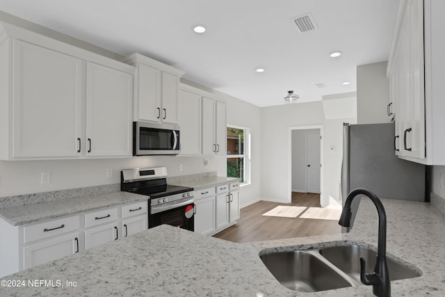 kitchen with light stone countertops, sink, white cabinets, and stainless steel appliances