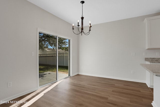 unfurnished dining area with dark hardwood / wood-style floors and an inviting chandelier