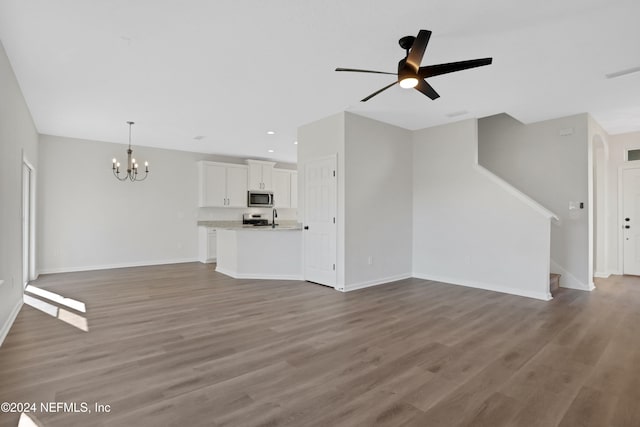 unfurnished living room featuring ceiling fan with notable chandelier and hardwood / wood-style flooring