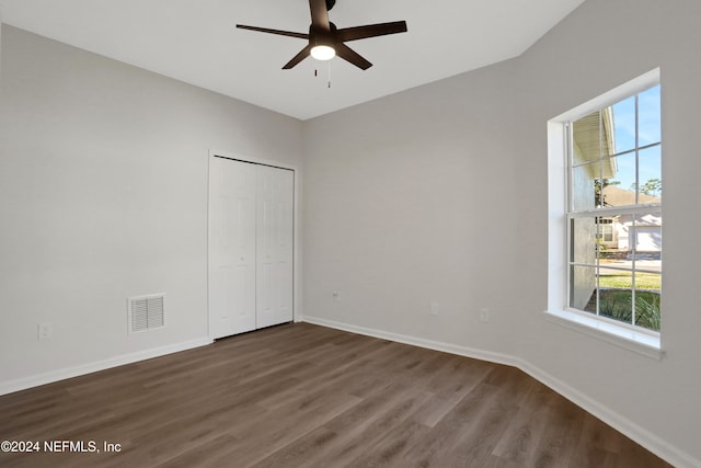 unfurnished bedroom featuring multiple windows, ceiling fan, a closet, and dark wood-type flooring