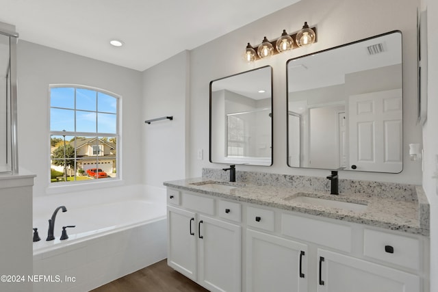 bathroom with plus walk in shower, hardwood / wood-style floors, and vanity