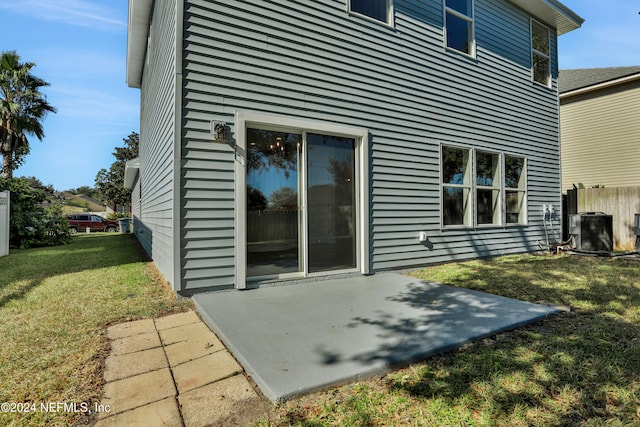 back of property featuring a lawn, cooling unit, and a patio