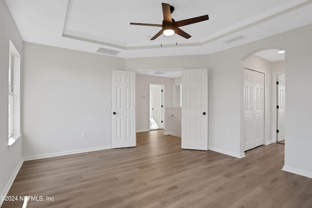 unfurnished room featuring hardwood / wood-style floors, ceiling fan, and a raised ceiling