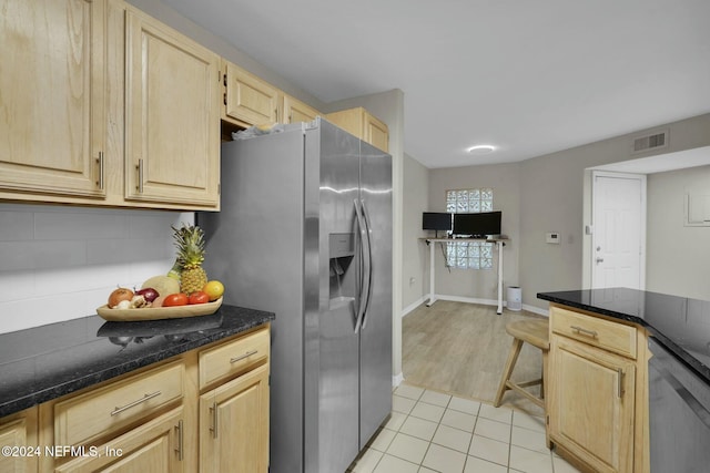 kitchen featuring dark stone countertops, stainless steel fridge with ice dispenser, light brown cabinetry, and light wood-type flooring